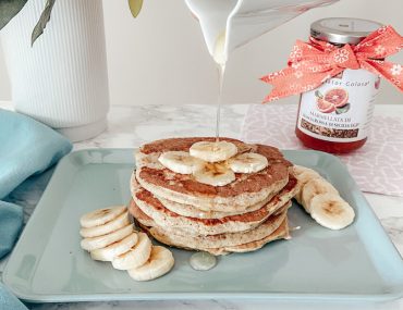 pancakes integrali serviti su vassoio con banana a fette e miele